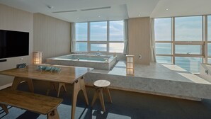 Une chambre d’hôtel moderne dotée d’une grande fenêtre, d’une baignoire, d’un coin repas et d’un téléviseur à écran plat.