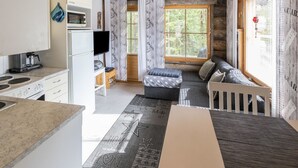 Ett modernt kök med spis, diskho och en platt-TV. Det finns också en mysig sittgrupp med en soffa och ett litet bord.