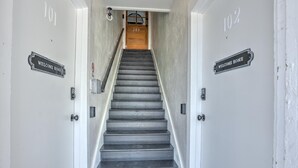 Un escalier surmonté d’une porte en bois, avec les numéros « 203 » et « 102 » indiqués de part et d’autre.