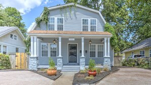 A two-story house with a porch, numbered 1954, featuring stone pillars and potted plants.