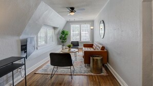 A modern living room with a ceiling fan, a sofa, a coffee table, and a TV mounted on the wall.