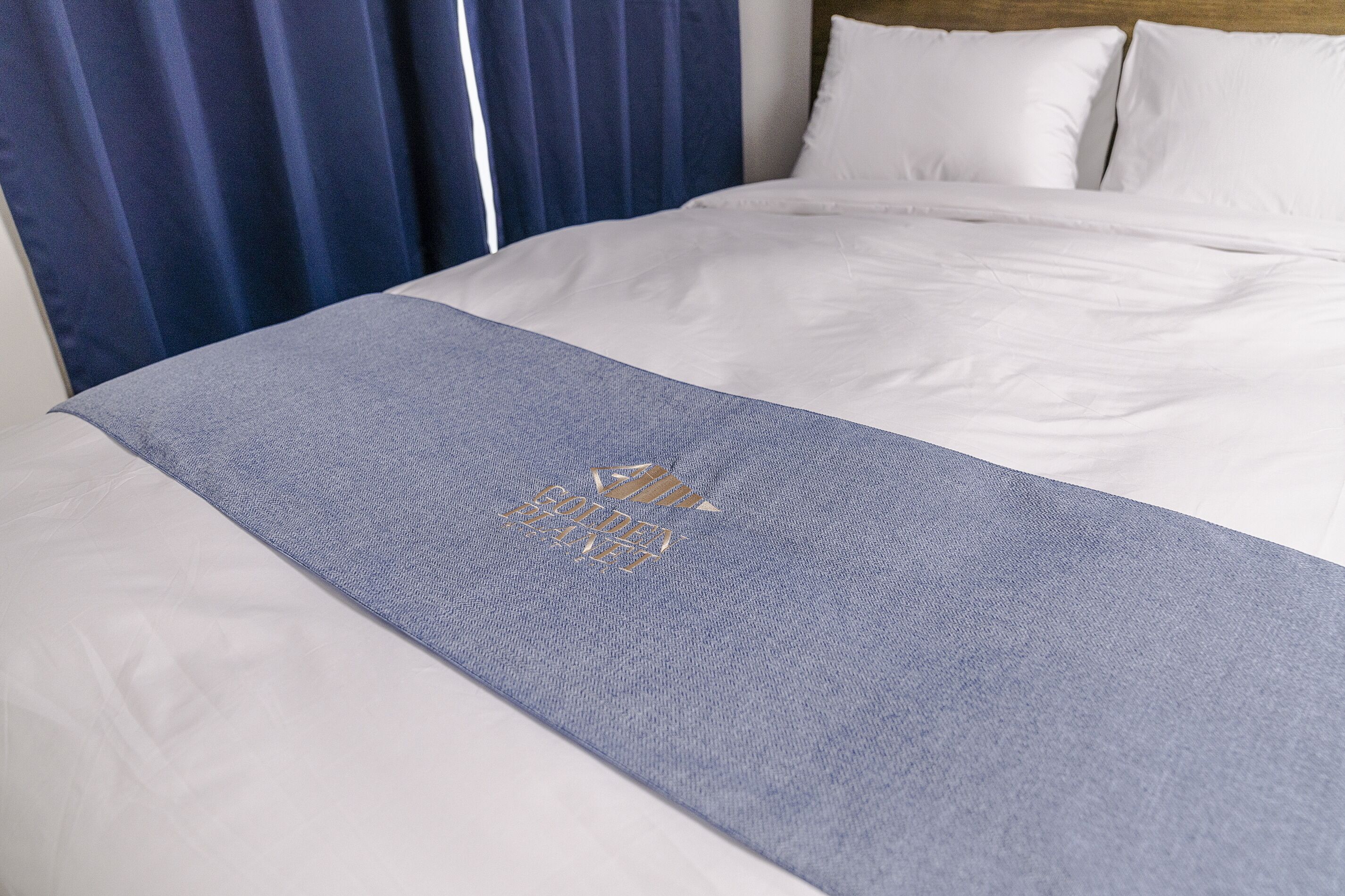 A neatly made bed with white linens and a blue bedspread.
