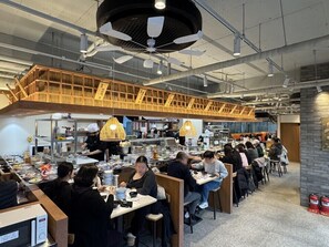 A restaurant with multiple dining areas, high ceilings, and industrial-style lighting. - Golden Planet Hotel & Resort (Icheon)