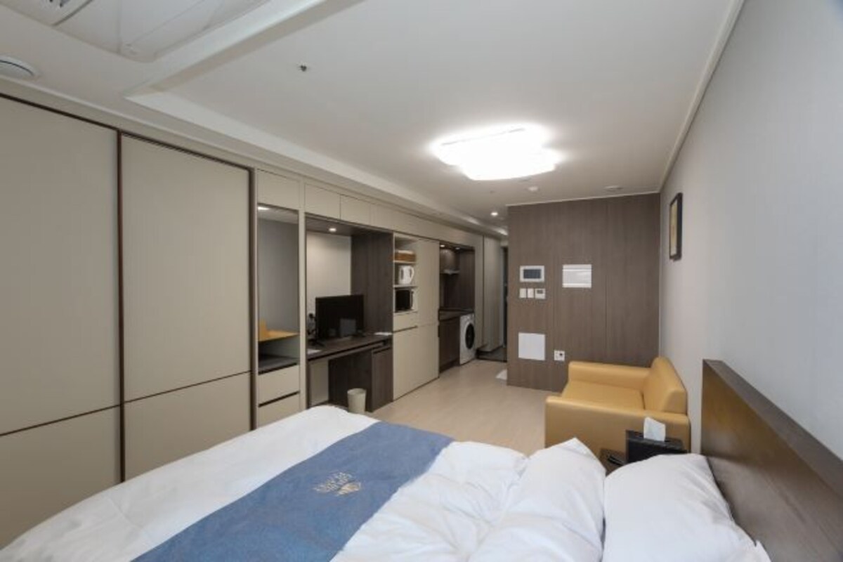 A hotel room with a bed, a desk, a chair, and a wardrobe.