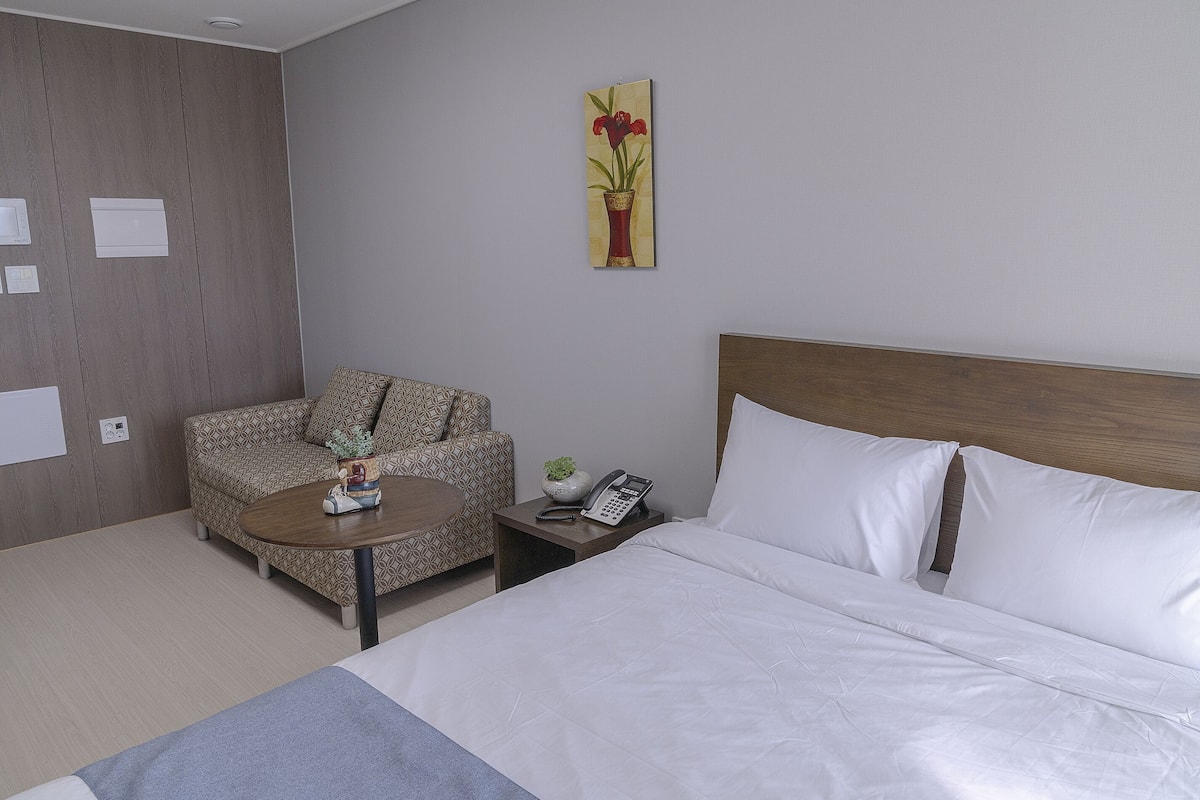 A hotel room with a bed, a sofa, a small table, and a nightstand.