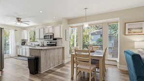 Una cocina moderna con armarios blancos, una isla central y un área de comedor con mesa y sillas.