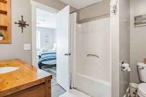 Een badkamer met een houten wastafelmeubel, een wit ligbad en een douchegordijn.