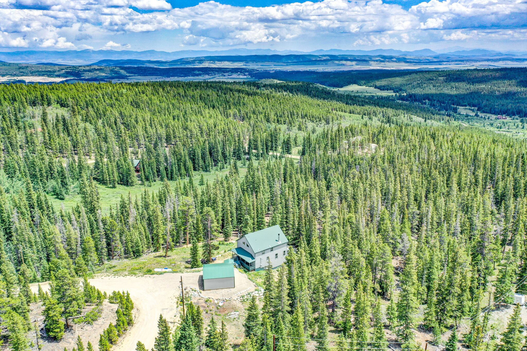 Une cabane entourée d’une forêt dense, offrant une vue dégagée sur les montagnes lointaines.