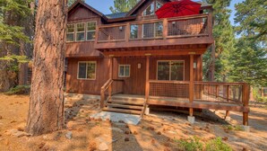 Une cabane en bois à deux étages, dotée d’un balcon, d’une véranda et d’un escalier menant à l’entrée.