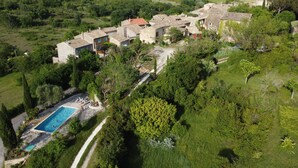 A villa with a swimming pool surrounded by lush greenery and hills in the background.