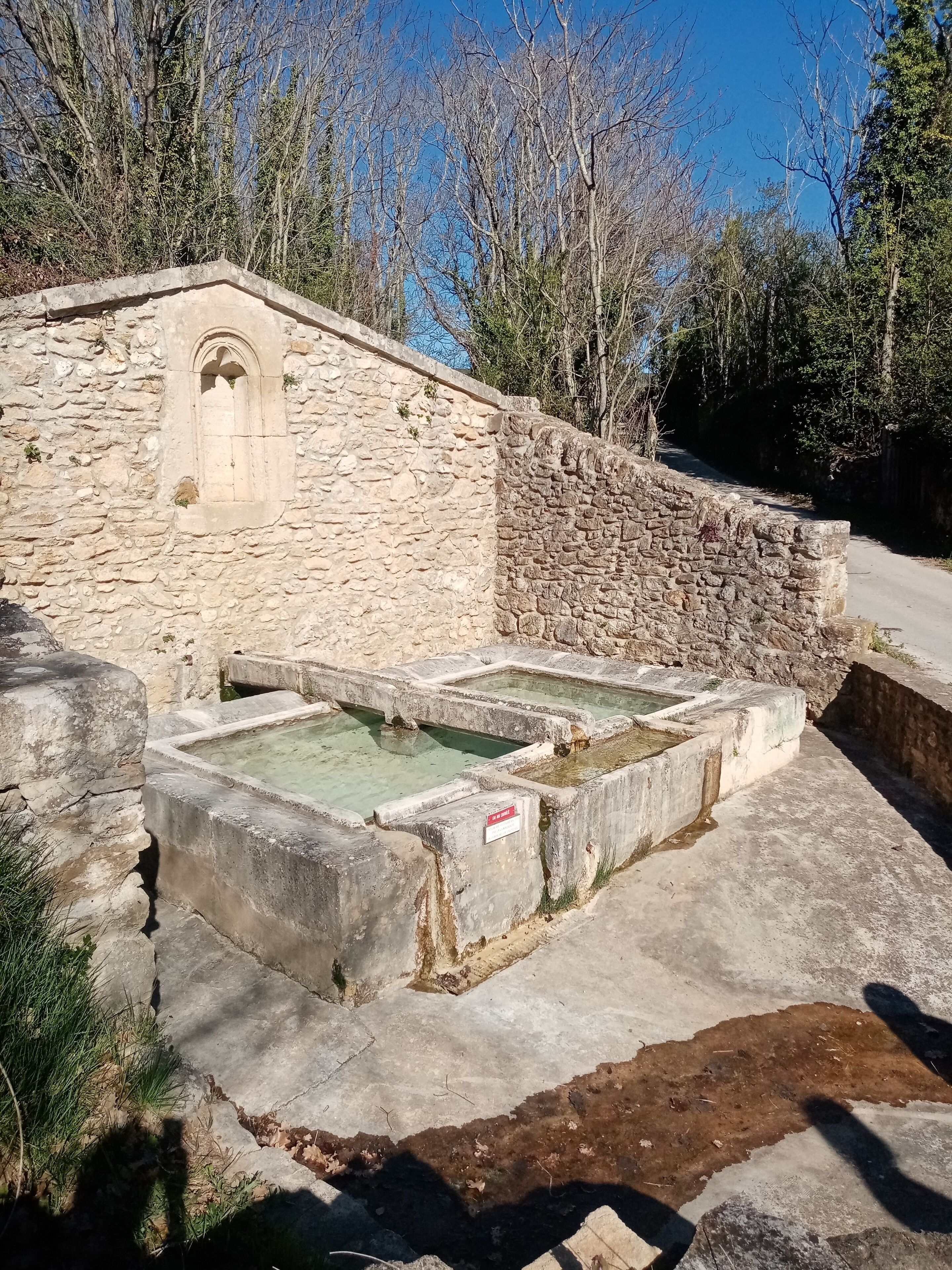 A stone building with a small arched window and a stone wall.