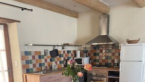 A kitchen with a wooden table and chairs, a tiled backsplash, and a white refrigerator.