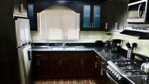 A kitchen with dark wooden cabinets, a stainless steel refrigerator, a gas stove, and a microwave.