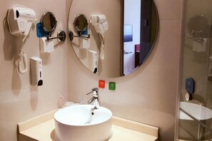 A bathroom with a sink, two hair dryers, a mirror, and a glass shower enclosure. - Geli Hotel (Shanghai Kangqiao Subway Station store, New International Expo Center ) (Shanghai)