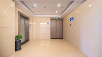 A hotel corridor with a door, an elevator, and a trash bin.