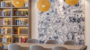 A dining area with a long table, multiple chairs, and a bookshelf filled with books.