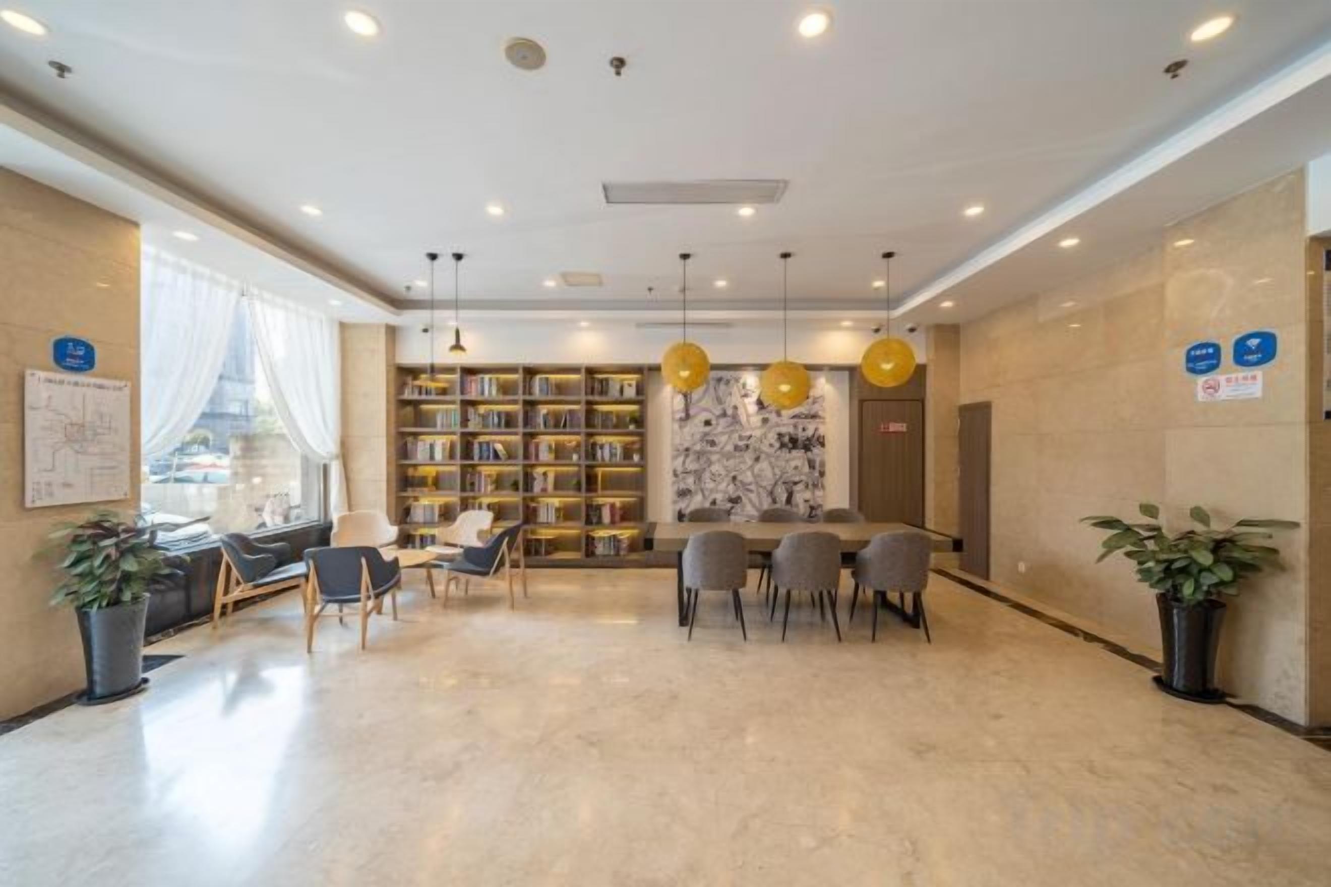 A hotel lobby with a seating area, a bookshelf, and a reception desk.