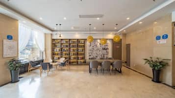A hotel lobby with a seating area, a bookshelf, and a reception desk.