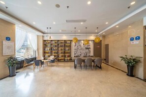 A hotel lobby with a seating area, a bookshelf, and a reception desk.