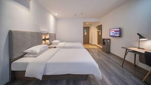 Quarto de hotel com duas camas, uma escrivaninha, uma televisão e aparelho de ar condicionado.
