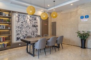 A conference room with a long table and chairs, a bookshelf, and a wall with a black and white abstract design.