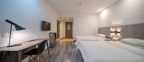 A hotel room with a desk, two beds, a TV, and a lamp.