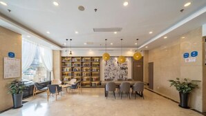 A modern hotel lobby with a marble floor, a seating area with chairs and a table, a bookshelf, and a large window with curtains. - Geli Hotel (Shanghai Kangqiao Subway Station store, New International Expo Center ) (Shanghai)