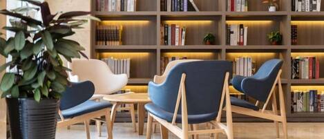 A modern library with bookshelves, seating, and a potted plant.