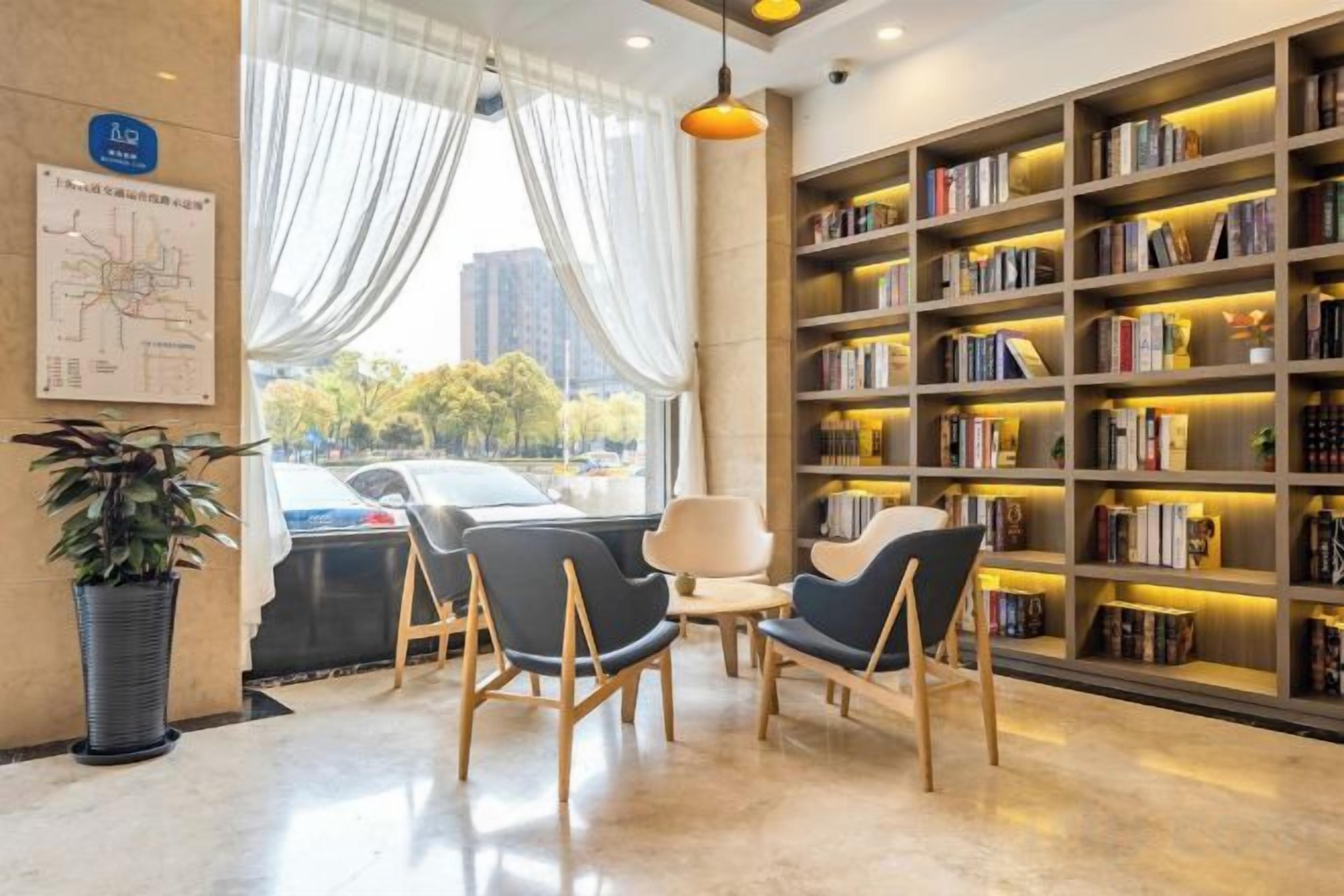 A modern library with bookshelves, seating, and a view of the outdoors.