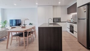 Et moderne køkken med en central ø, indbygget mikrobølgeovn og et stålskab.