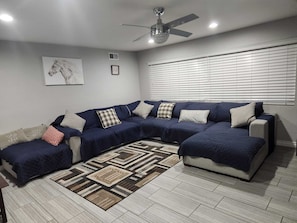 A living room with a sectional sofa, a patterned rug, and a ceiling fan. - VeryPrivateHouse in Riverside,3bedrooms& 2 1/2 bathroom house w/Pool & big Patio (Riverside)