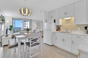 A modern kitchen with white cabinets, a built-in oven, and a large window overlooking a balcony.