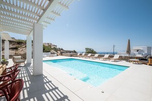 A pool area with lounge chairs and a pergola.