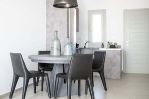 A modern dining area with a round table, four chairs, and two decorative bottles.