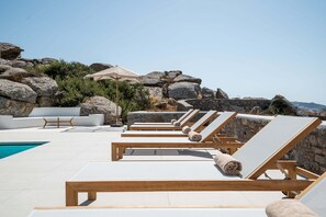 A poolside area with lounge chairs, a table, and a large umbrella.