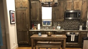 A kitchen with wooden cabinets, a central island, a microwave, an oven, and a tiled backsplash.