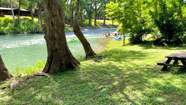 A riverside park with picnic tables and a canoe rental area.