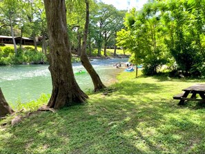 Un parc au bord de la rivière, équipé de tables de pique-nique et d’un espace de location de canoës.