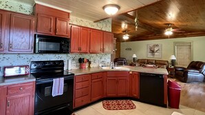 A kitchen with wooden cabinets, a microwave, stove, and a dishwasher. - Cabin On The Lake (Hemphill)