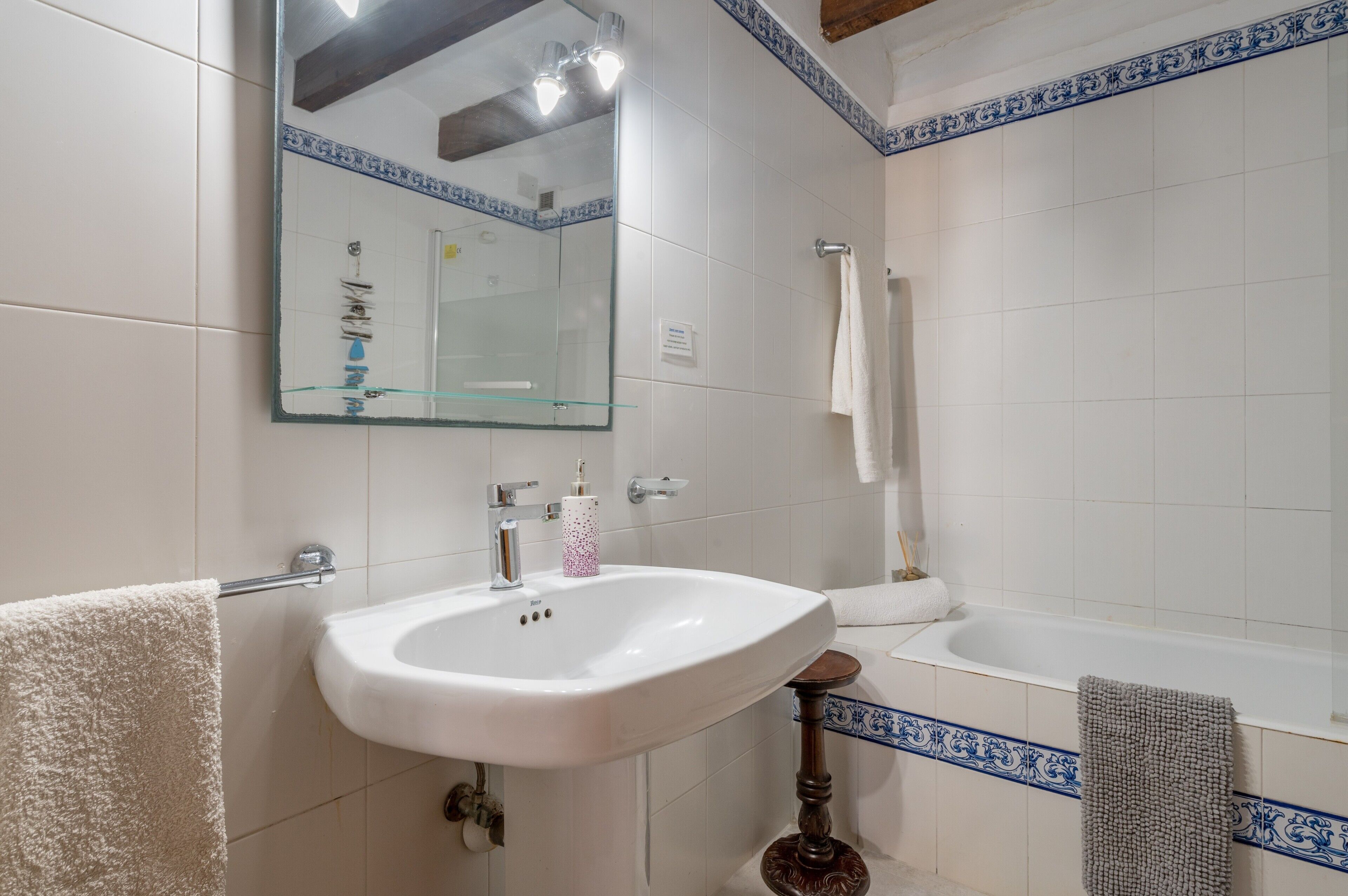 A bathroom with a white sink, a mirror, a bathtub, and a towel rack.