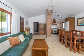 A living room with a sofa, a wooden table, and a dining area with chairs and a table.