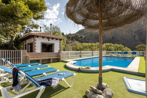 Un espace piscine avec des chaises longues, un petit bâtiment et une clôture blanche.