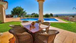 Espaço ao ar livre coberto com piscina, móveis de vime e vista para a paisagem.