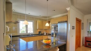 Uma cozinha moderna com ilha central, eletrodomésticos de aço inoxidável e iluminação pendente.