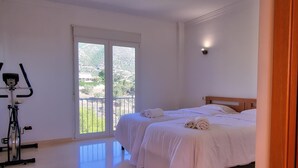 Quarto com cama, varanda e bicicleta ergométrica.