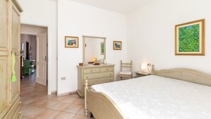 Een slaapkamer met een bed, een dressoir, een spiegel en wanddecoratie.