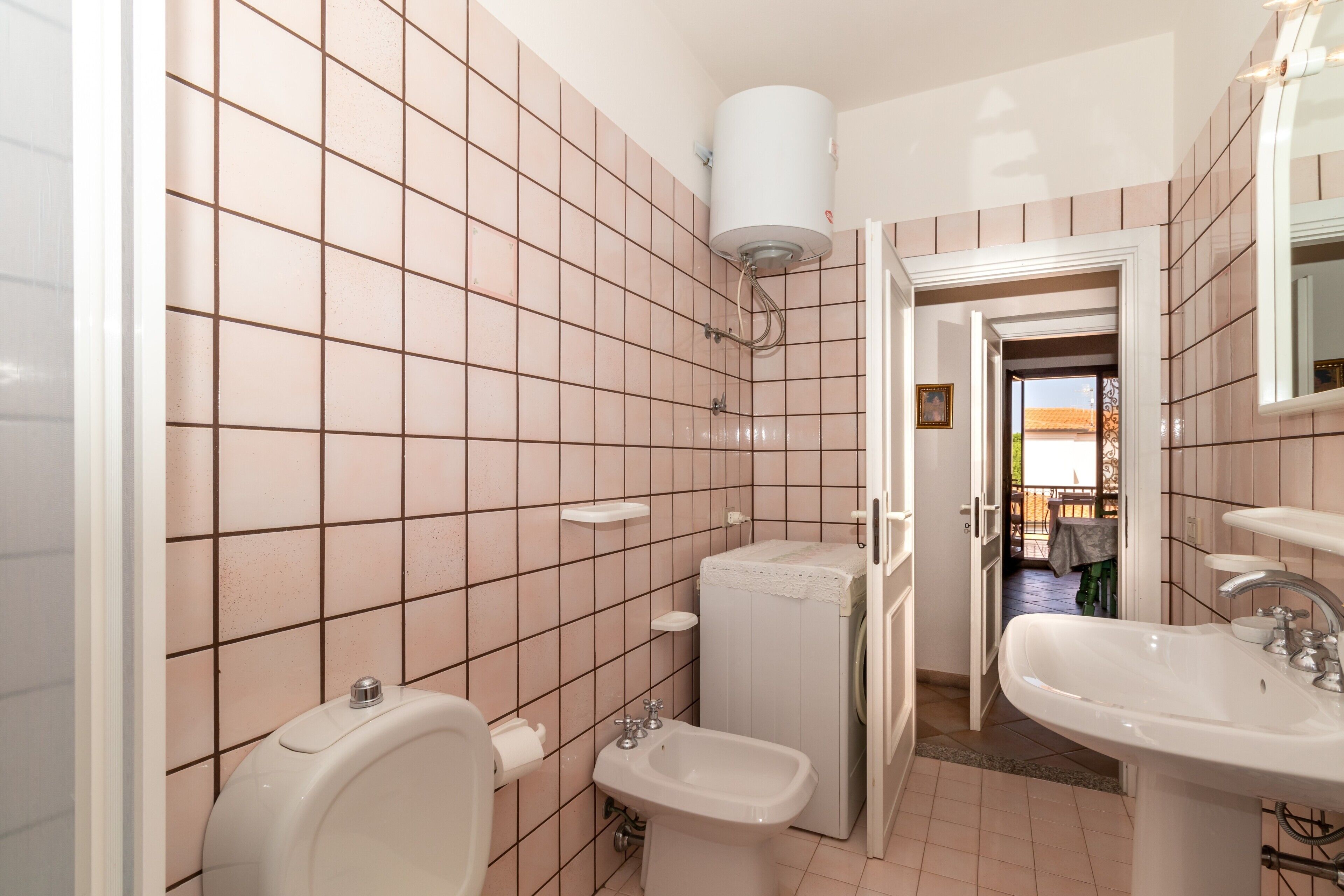Un baño con inodoro, bidé, lavabo y lavadora.