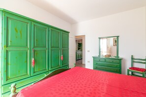 A bedroom with a large bed, green wardrobe, and a dresser with a mirror.