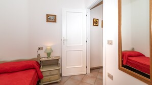 A bedroom with a bed, a nightstand, a mirror, and a door leading to another room. - Apartment  Azalea with Balcony & Wi-Fi (Valledoria)