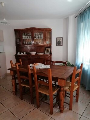 Ein Essbereich mit einem Holztisch und Stühlen, einem Schrank mit Glastüren und einem gerahmten Bild an der Wand.
